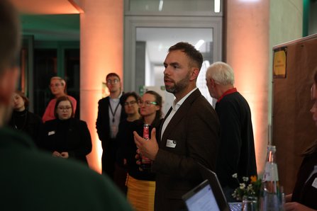 Mann spricht, mehrere Personen drumherum