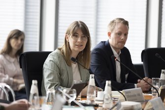 Drei Personen im Konferenzraum.