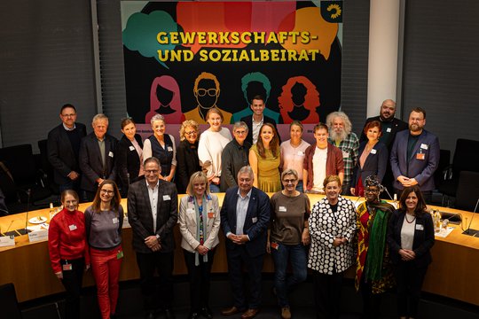 Gruppenfoto Gewerkschafts- und Sozialbeirat 2025. Viele Leute stehen in zwei Reihen in einem Sitzungssaal nebeneinander