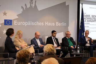 6 Personen sitzen auf der Bühne, der Herr ganz rechts redet gerade.