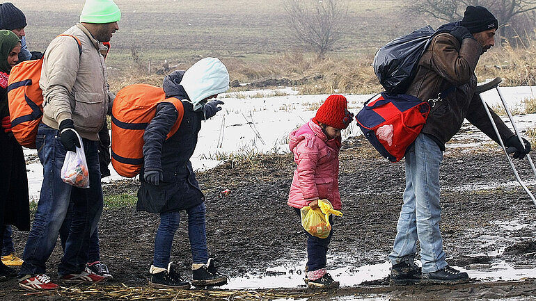Geflüchtete laufen im Januar 2016 auf einem sehr matschigen Weg von Macedonien zu einem vorrübergehenden Flüchtilingscamp in der Stadt Miratovac, an der Grenze zwischen Serbien und der Republik Nord-Macedonien.
