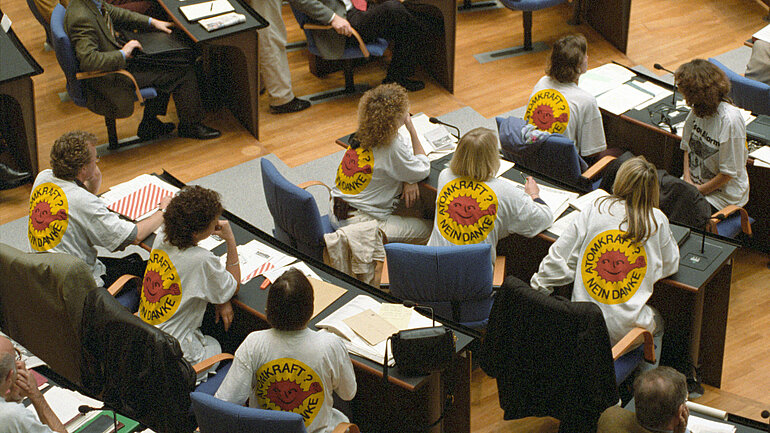 Die Abgeordneten von Bündis 90/Die Grünen streiften sich bei der Rede von Bundesumweltministerin Merkel am 24.11.1994 im Deutschen Bundestag in Bonn aus Protest gegen die Castor-Transporte T-Shirts mit dem Aufdruck "Atomkraft? Nein Danke" über. 