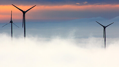 Drei Windräder über einem Nebelmeer
