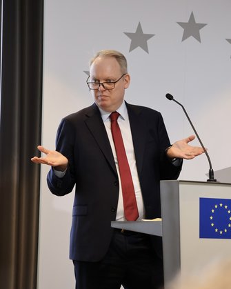 Ein Mann im Anzug mit roter Krawatte spricht am Redepult.