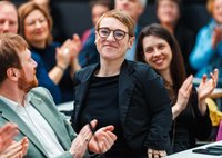 Simone Fischer in der Fraktionssitzung umgeben vom Applaus weiterer grüner Bundestagsabgeordneter. 