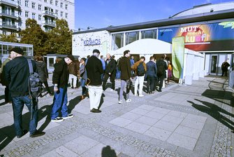 Eine lange Schlange aus Personen vor dem Veranstaltungsgebäude.